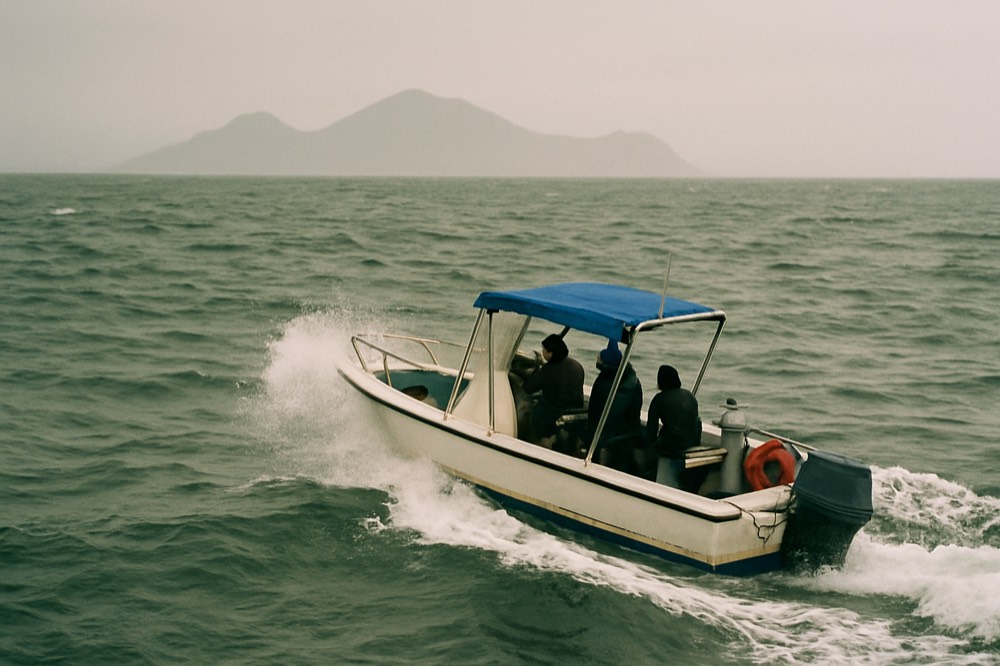 A dive boat pitching in open ocean swell near distant volcanic islands