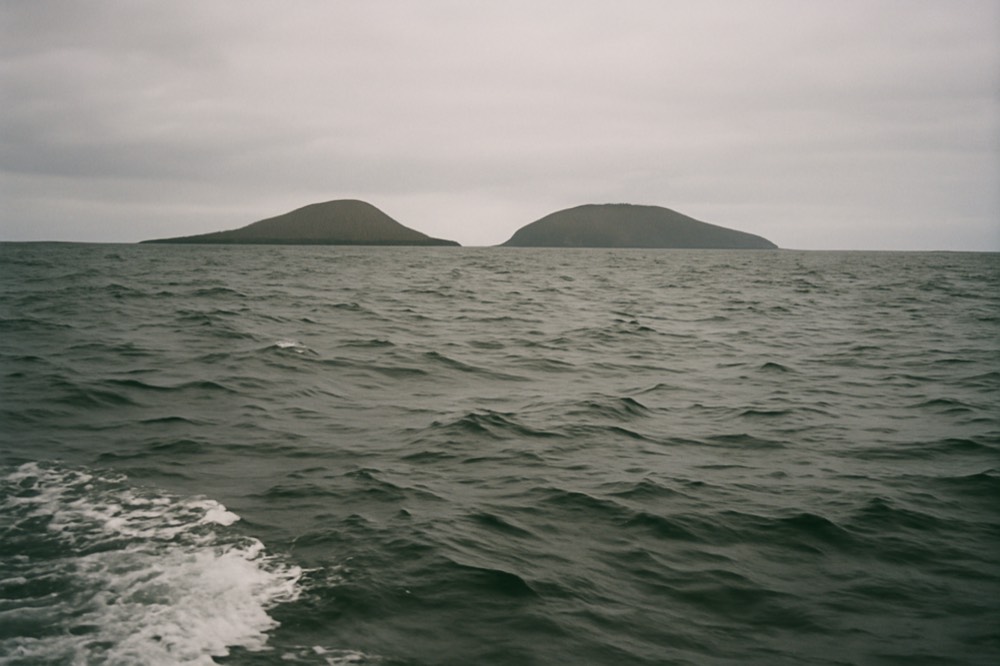 Whitecaps on open blue water between two distant volcanic islands
