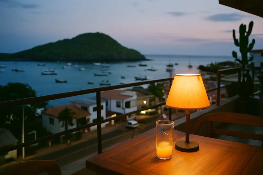 A hotel terrace overlooking a small island harbour at sunset