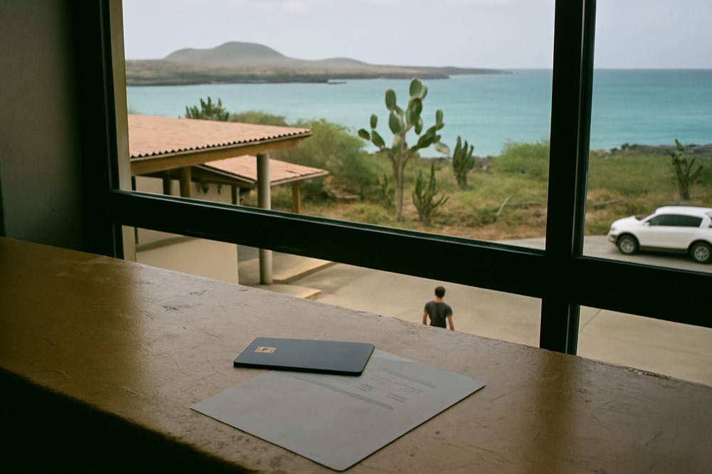 A credit card and printed itinerary on a desk in front of a window overlooking the sea